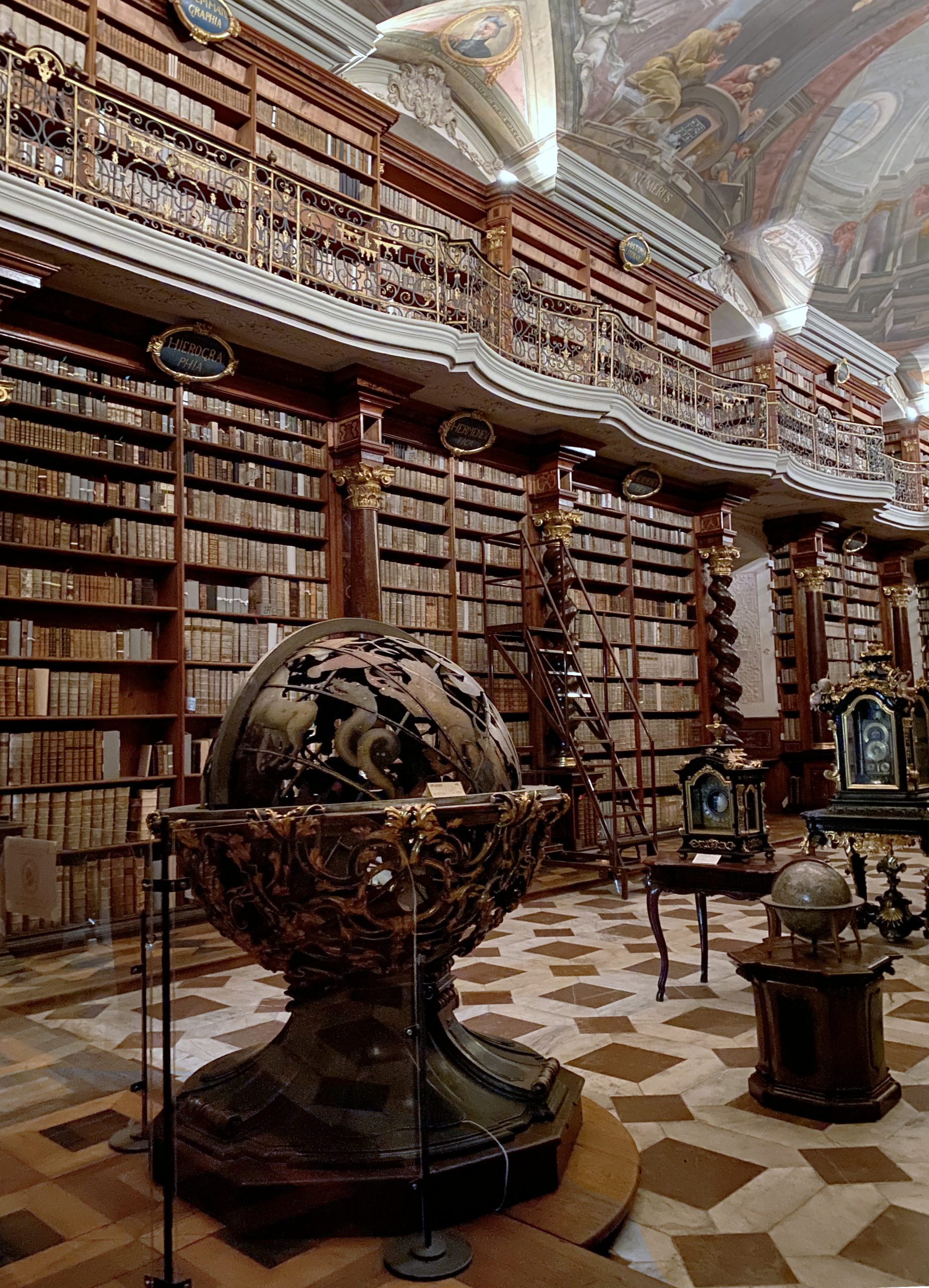 Detail of the interior of the Baroque Library Hall, Klementinum in Prague showing a large globe and towering wooden bookcases
