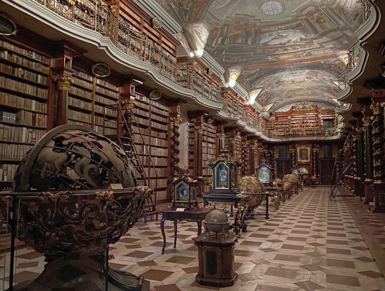 The Baroque Library Hall, Klementinum in Prague complete with frescoed ceilings, tall wooden bookshelves and a series of globes and clocks down the centre of the hall